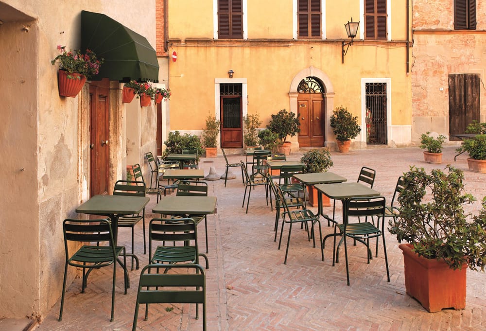 Cappottine verdi sopra gli ingressi di una piazza con tavoli all'aperto