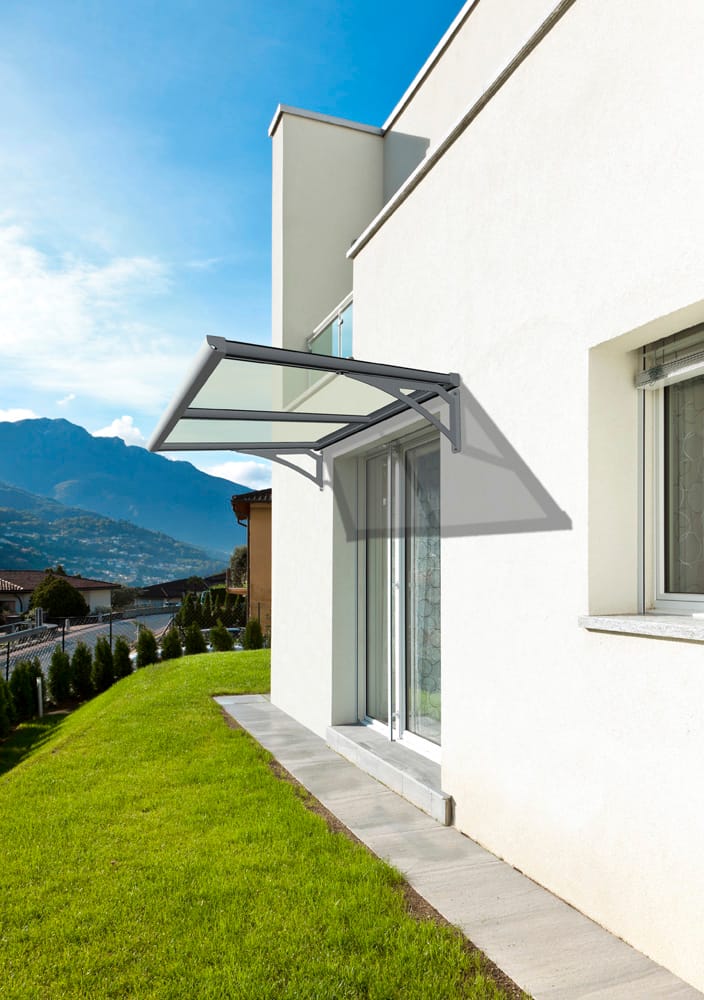 Pensilina trasparente con supporti in acciaio sopra la porta-finestra di una casa